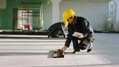 İnşaat alanında güneşli bir günde inşaat malzemelerine bakmak için dijital tablet kullanan genç ve güzel bir mühendis kadın bina planına bakıyor. ARRI Alexa Mini 'de çekilen.