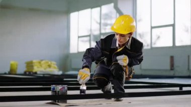İnşaat alanında çalışan karizmatik kadın müteahhit inşaat malzemelerini boyamak için boya fırçası kullanıyor ve koruyucu kask ve üniforma giyiyor. ARRI 'de çekilen