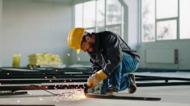 In a large construction site hard working man using the disc welding machine to cut some metals and creating big sparks. Shot on ARRI Alexa Mini.