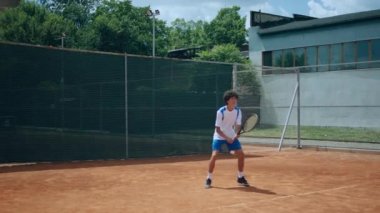 Genç tenisçi raketle tenis topuna sert vuruyor ve sonunda heyecanlanıyor ve dizlerinin üstüne çöküp zaferi kutluyor. ARRI Alexa Mini 'de çekilen
