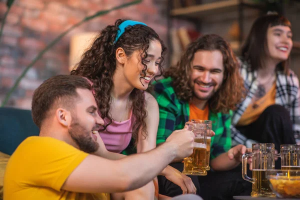 Attractive two ladies and handsome guys meeting together to watching on tv channel sport match they getting excited when their team wins and cheers with beer. Portrait