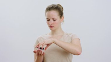 Taking video in front of the camera charismatic beautiful woman looking straight to the camera and apply her moisturising favourite cream on her face concept of skin care. 4k