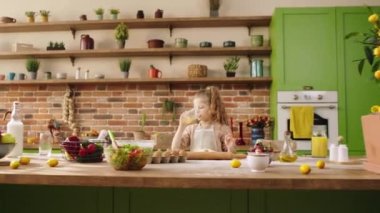 At the kitchen island beautiful girl take some orange juice and continue to mix the dough to prepare a delicious dessert for all family. Shot on ARRI Alexa Mini