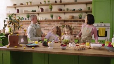 Happy and Funny family al together with kids playing and cooking together healthy breakfast at the kitchen island in the morning.