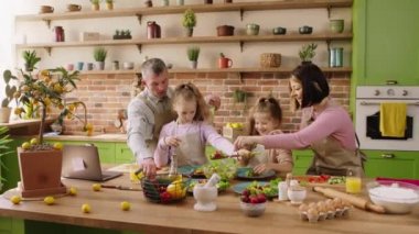 Excited and beautiful family members in the morning at the kitchen preparing happy the breakfast together they cut some salad and get ready to eat add the food on the big plate. 4k