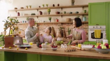 In the morning at the kitchen at home happy and smiling large family preparing the healthy breakfast together they cut some vegetables and salad.