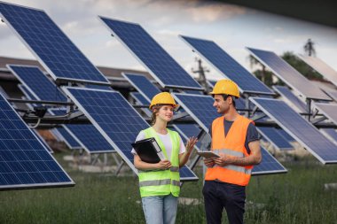 Concept of renewable energy and ecological environment group of engineers young team analysing together the cleanliness of photovoltaic solar panels they wearing safety equipment and helmets. Portrait