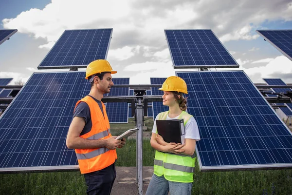 Concept of green energy at solar power farm the ecological engineer man and his assistant walking through the photovoltaic solar panels and analysing the result of green energy and renewable energy