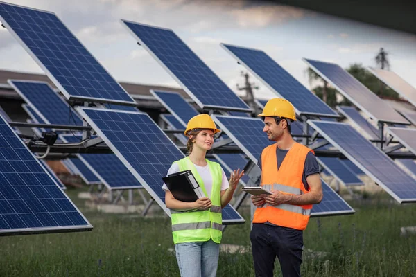 Concept of renewable energy and ecological environment group of engineers young team analysing together the cleanliness of photovoltaic solar panels they wearing safety equipment and helmets. Portrait