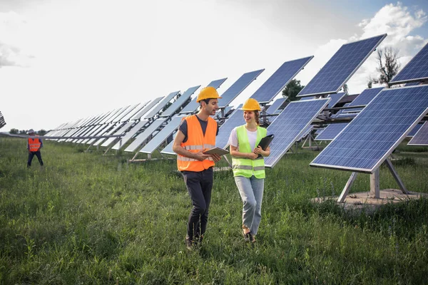 Business man and woman dressed in the suits having a deal, shaking hands while standing on a solar power station.