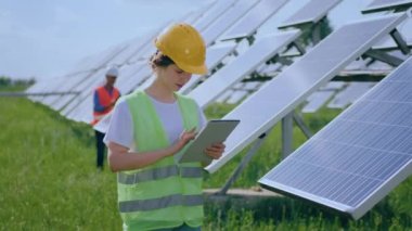 Young female ecological engineer uses digital tablet she collected efficient information about solar panels at photovoltaic solar farm concept of ecology green energy.