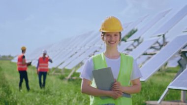 Large smiling ecological engineer woman posing in the middle of photovoltaic solar panels farm concept of green energy and ecological energy. 4k