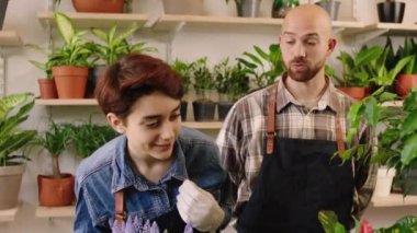 In front of tue camera in the floral store the sale assistant man and the florist lady have a conversation while analysing the flowers form the pot. 4k