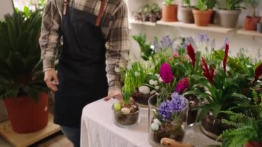 Concept of small business floral store the owner man entrepreneur Caucasian looking make a nice composition for Easter to sale for customer. 4k