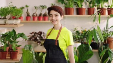 Portrait of a beautiful and pretty female florist in the floral store posing in front of the camera smiling large and feeling excited. 4k