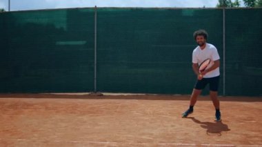 In a sunny day good looking man tennis player hitting the ball with the racket very professional on the outdoor tennis court. 4k