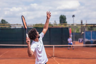 In a sunny day good looking man tennis player hitting the ball with the racket very professional on the outdoor tennis court.