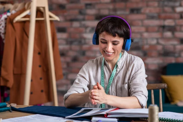 Modern fashion office awesome looking fashion designer woman threw up the buttons and enjoy the moment while listening music from the headphones and working at her new collection of clothes. Portrait