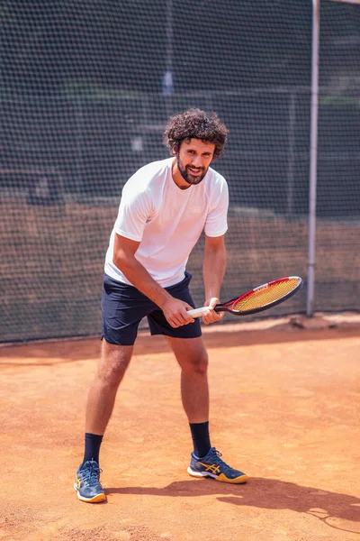 Handsome man is playing tennis on tennis court outdoors.