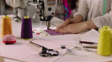 In front of the camera taking video details of a professional sewing machine dressmaker woman sew a dress very carefully
