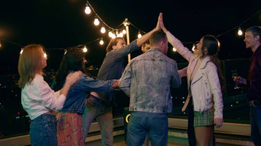 Çok ırklı insanlar terasta eğleniyor. Dans etmekten ve şampanya içmekten zevk alıyorlar..