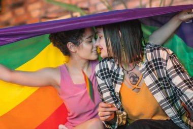 Concept of LGBT freedom equality friendship happy lesbian couple very attractive ladies hugging each other and spending romantic time at home on the sofa in living room. Portrait