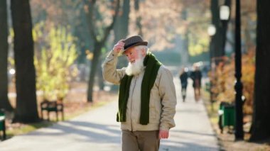 Attractive old man in the middle of the park in the late autumn day enjoy the nature he take of his hat then put back in front of the camera. Shot on ARRI Alexa Mini.