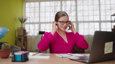 Modern office place amazing looking female call centre assistant take her headset and start to working on the laptop online she discussing with some client she try to resolve some problems. 4k