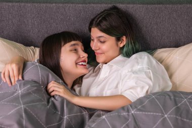 In the bedroom lesbian couple spending romantic time together they hugging each other and touching with love concept of LGBT equality freedom friendship.