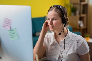 Laptop ile çalışma ve headseat ile mutlu yüz gülümseyen giyen güzel genç operatör kadın silah kameraya bakarak geçti. Olumlu bir kişi.