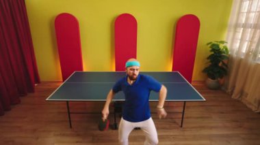 Attractive young man ping pong player dancing and moving funny before start to play on the table tennis he looking to the camera and smiling. 4k