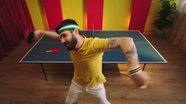 Smiling funny charismatic guy dancing and moving crazy in front of the camera he holding the paddles on hands after he win the table tennis game. 4k