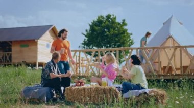 Group of multiracial friends meeting together at the campsite they have a picnic time together discussing drinking enjoy the time and chilling at the nature.