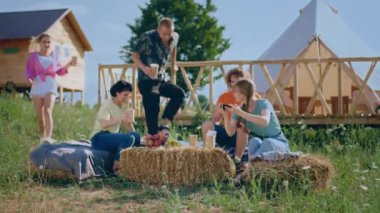 Good time for a big group of friends multiracial meeting at campsite they enjoy the time together sitting down on the haystack and make pictures for memories. Shot on ARRI