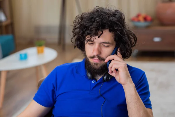 Good looking guy very excited explains something while sitting on the chairs at home using the laptop he working online from home and have a online conversation he get nervous and take off his headset