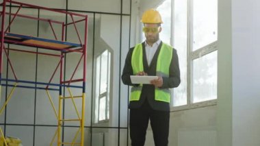 Young man engineer taking pictures with digital tablet at construction site he wearing safety equipment and protective glasses.