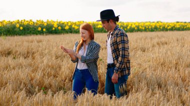 İki çiftçi kadın ve adam tarımsal tarım sektörünün ortasında bir şeyi analiz ediyorlar..