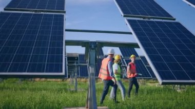 Taking video at photovoltaic solar panels walking through the farm ecological engineer and investor they analysing the plan of work together discussing.