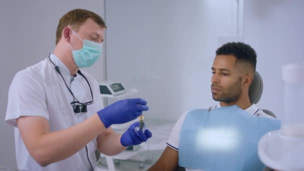 Сучасній Стоматологічній Клініці Лікар Стоматолог Показує Пацієнту Працює Імплантат Пояснює — стокове відео