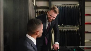 Happy manager Caucasian man have a good conversation with the consultant in a suit shop they smiling large and feeling happy. 4k