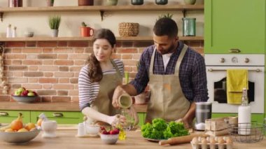 Awesome couple multiracial together in the morning have a healthy breakfast they add some smoothie on the glasses and start to drink then looking to each other with love. Shot on ARRI Alexa Mini