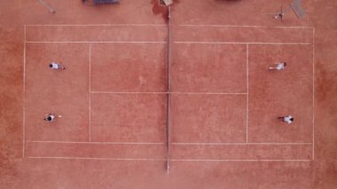 Taking video from the up with drone on the tennis court two team starting a new game they came to each other and shaking hands before start the match. 4k