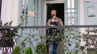 Yakışıklı girişimci ve çiçekçi. Çiçekçinin sahibi. Kahvesini aldı ve dükkânın önüne geldi. 4k