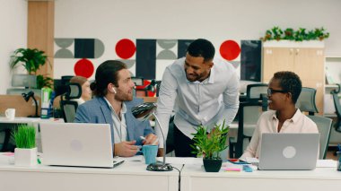 Büyük, parlak, modern bir ofiste, üç meslektaştan oluşan bir grup iş hakkında küçük bir sohbet yapıyorlar..