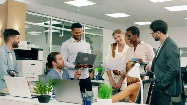 Büyük bir grup iş arkadaşı ve yönetici büyük bir modern ofiste dostça bir toplantı yapıyorlar..