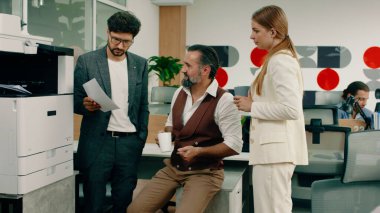 Ofisteki üç meslektaşın hareketli bir görüntüsü dizüstü bilgisayarlarına bakıyor ve birbirlerine iş hakkında tavsiyelerde bulunurken, diğer üç işçi de kendi aralarında konuşuyor. Portre