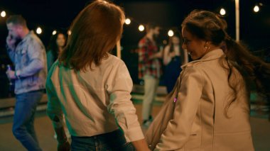 Bir grup çok ırklı insan partide şampanya içerek ve terasta eğlenerek eğleniyor..