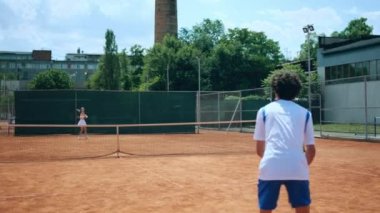 Kil kortunda şampiyonluk için antrenman yapan iki genç tenisçi raketle topa sert bir şekilde vurarak konsantre oldular..