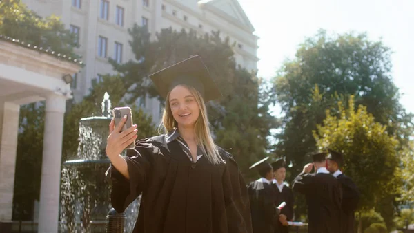 아름다운 대학원생 스마트폰으로 졸업장이 비디오를 만들고 있습니다 그녀는 정원에서 학생들 — 스톡 사진