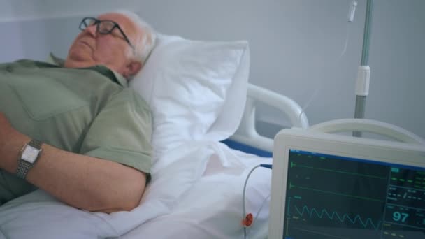 Hastane Odasındaki Yaşlı Adam Ayakta Kalp Atışlarını Ölçerken Yatağı Oluşturur — Stok video